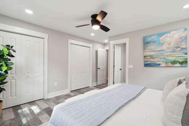 bedroom with light wood-type flooring, baseboards, two closets, and recessed lighting