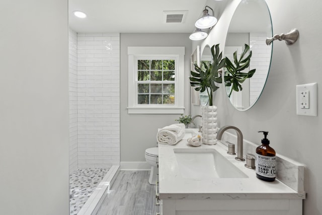 full bath with toilet, vanity, visible vents, baseboards, and a stall shower