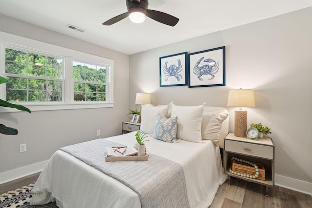 bedroom featuring a ceiling fan, baseboards, visible vents, and wood finished floors