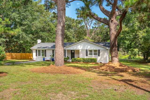 single story home with a front lawn, a chimney, fence, and brick siding