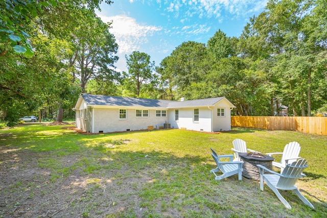 rear view of property with a yard, an outdoor fire pit, crawl space, and fence