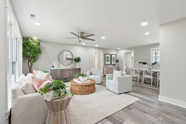 living area featuring baseboards, ceiling fan, light wood-type flooring, and recessed lighting