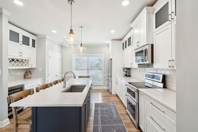 kitchen with a kitchen breakfast bar, a sink, beverage cooler, stainless steel appliances, and a center island with sink