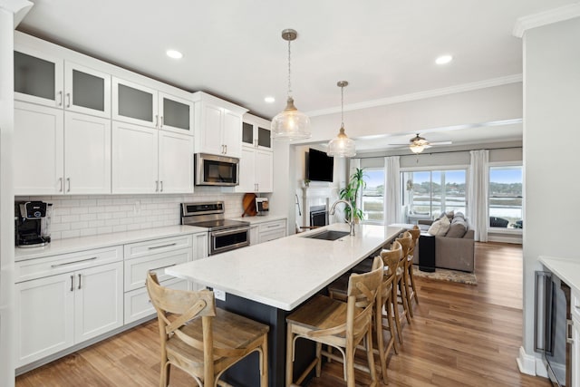 kitchen featuring a kitchen breakfast bar, open floor plan, crown molding, appliances with stainless steel finishes, and a sink
