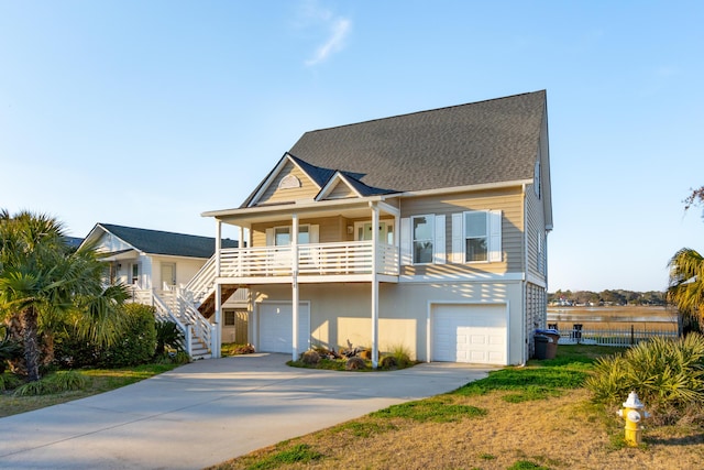 beach home with covered porch, a garage, concrete driveway, stairway, and stucco siding
