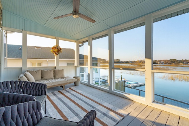 sunroom featuring wood-type flooring, floor to ceiling windows, a ceiling fan, and a water view