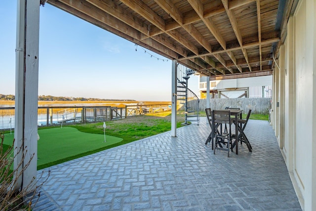 view of patio / terrace featuring a water view, outdoor dining space, fence, and stairs