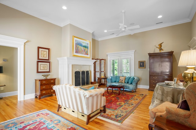 living room featuring light wood-type flooring, ceiling fan, and ornamental molding