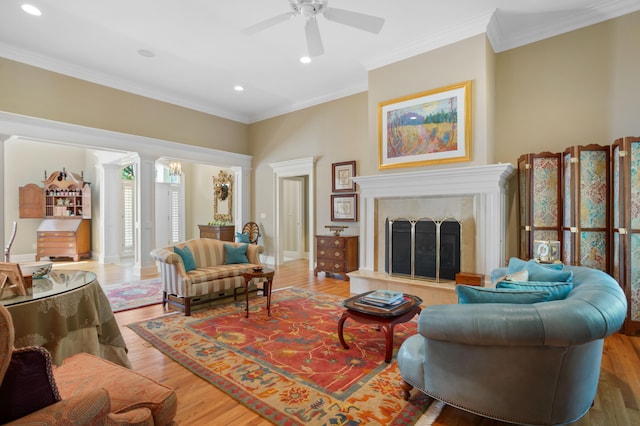 living room featuring hardwood / wood-style floors, ceiling fan, a fireplace, and ornamental molding