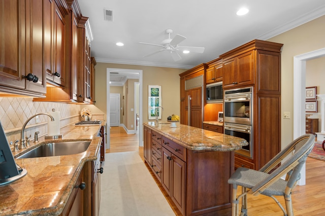 kitchen featuring light hardwood / wood-style flooring, light stone countertops, sink, built in appliances, and ceiling fan