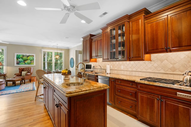 kitchen with light hardwood / wood-style floors, an island with sink, hanging light fixtures, sink, and ceiling fan