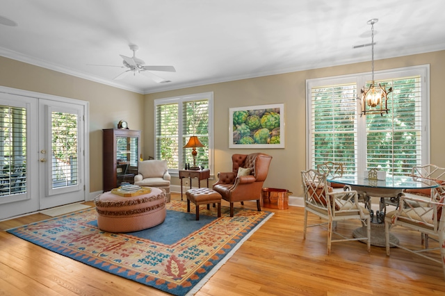 sitting room featuring crown molding, ceiling fan with notable chandelier, light wood-type flooring, and french doors