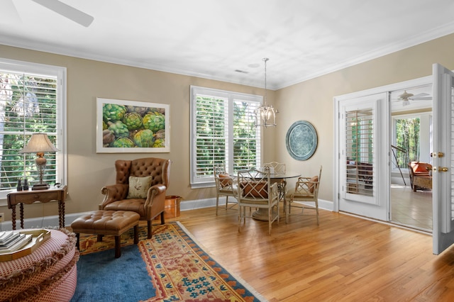 interior space with hardwood / wood-style floors, ceiling fan with notable chandelier, a wealth of natural light, and ornamental molding