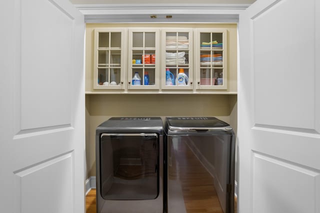 laundry area with hardwood / wood-style floors, cabinets, and washer and dryer