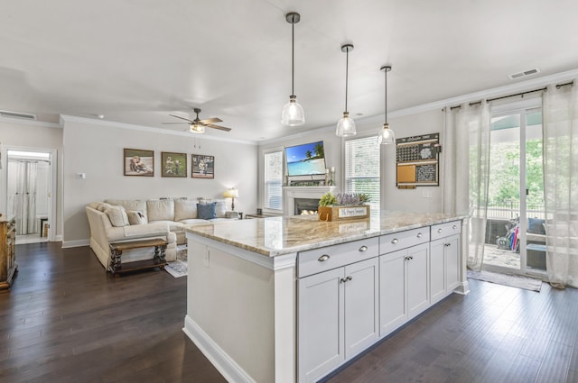 kitchen with white cabinetry, light stone counters, decorative light fixtures, and ornamental molding