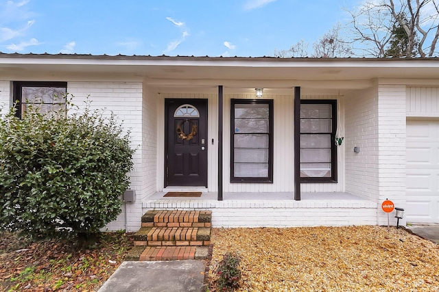 doorway to property featuring covered porch and brick siding