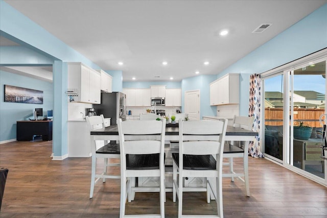 kitchen featuring white cabinets, dark hardwood / wood-style floors, a kitchen breakfast bar, and stainless steel appliances