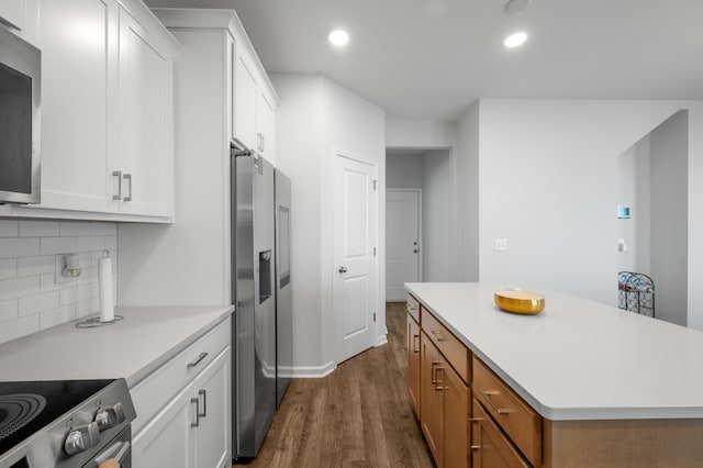 kitchen with stainless steel fridge, backsplash, white cabinetry, and a kitchen island