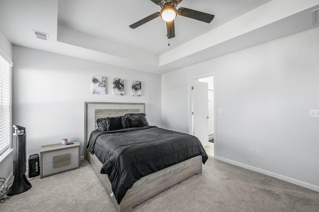 carpeted bedroom featuring ceiling fan and a tray ceiling