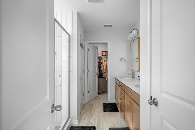 bathroom featuring a shower with door and vanity