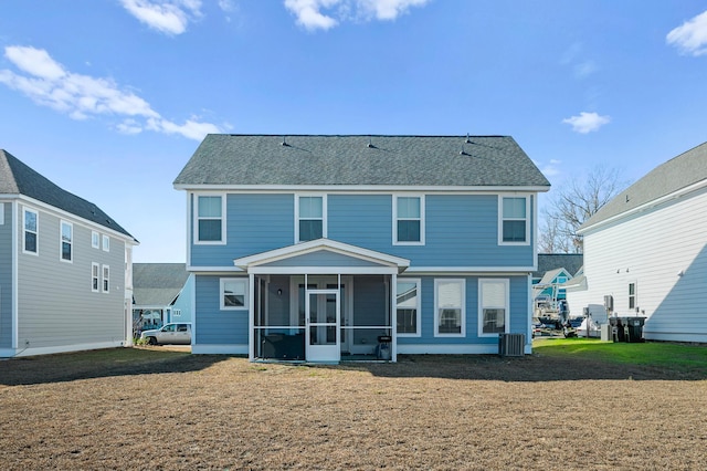 rear view of house with a sunroom, central air condition unit, and a lawn