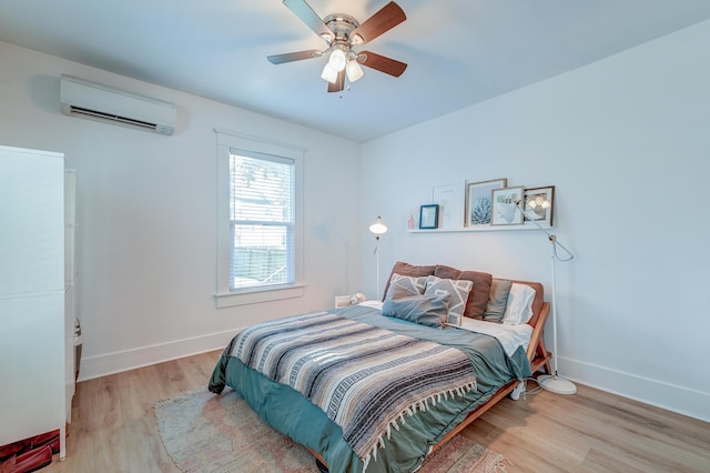 bedroom featuring ceiling fan, light hardwood / wood-style floors, and a wall mounted AC