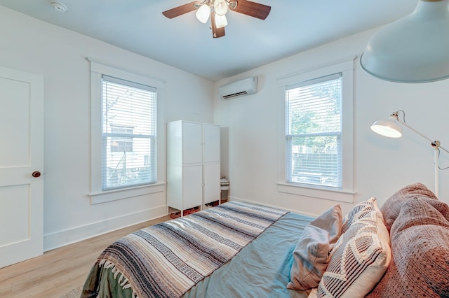 bedroom featuring light wood-type flooring, ceiling fan, and a wall mounted air conditioner