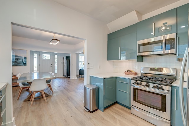 kitchen featuring decorative backsplash, green cabinets, light hardwood / wood-style flooring, and stainless steel appliances