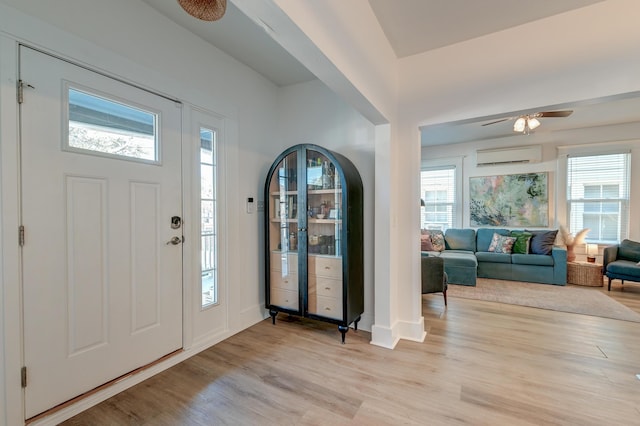 foyer entrance featuring light hardwood / wood-style floors and a wall unit AC