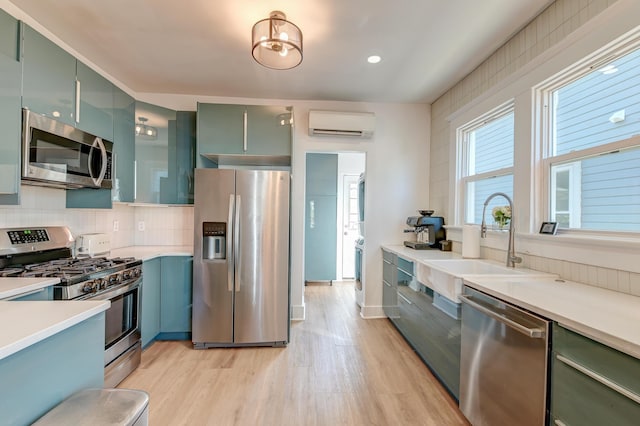 kitchen with appliances with stainless steel finishes, light hardwood / wood-style floors, sink, backsplash, and a wall mounted AC