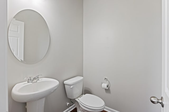 bathroom with toilet, baseboards, and a sink