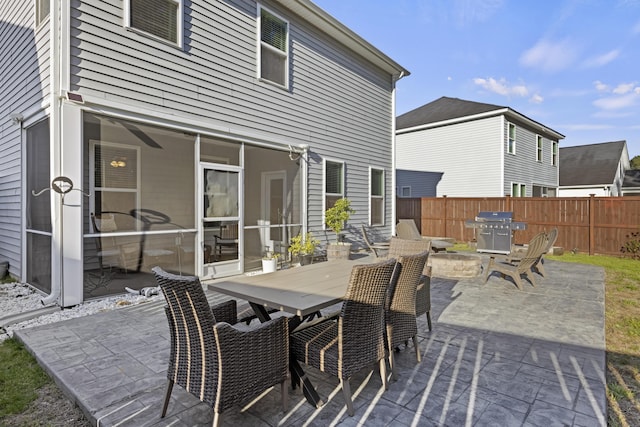 view of patio with outdoor dining space, a sunroom, fence, and grilling area