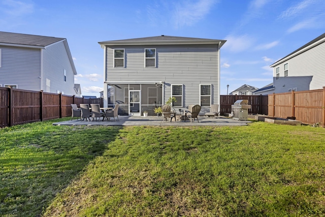 rear view of property featuring a sunroom, a patio area, a lawn, and a fenced backyard