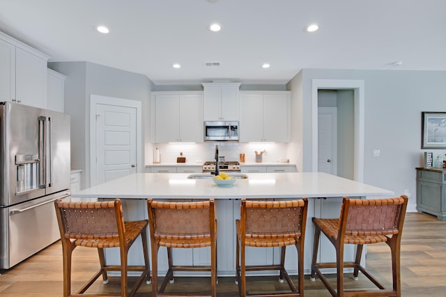 1607 Waterside Blvd, Moncks Corner, SC 29461 - kitchen with appliances with stainless steel finishes, tasteful backsplash, light wood-type flooring, white cabinets, and recessed lighting