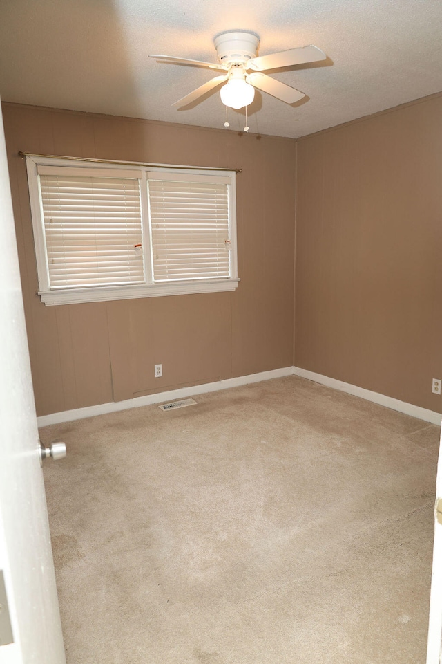 empty room with ceiling fan and light carpet