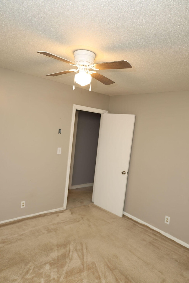 unfurnished room featuring a textured ceiling, light colored carpet, and ceiling fan