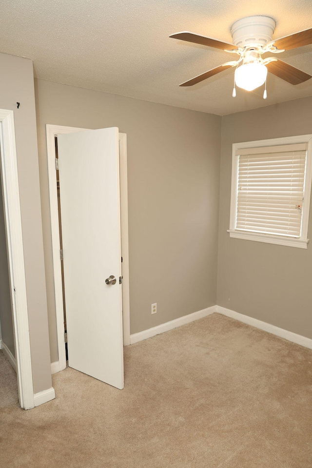 spare room featuring ceiling fan, light colored carpet, and a textured ceiling