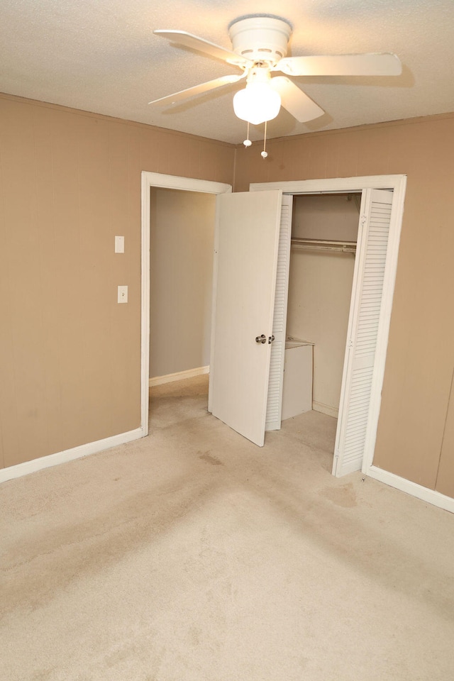 unfurnished bedroom featuring a closet, a textured ceiling, carpet flooring, and ceiling fan