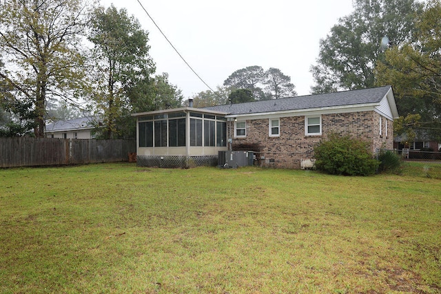 rear view of house featuring central AC unit, a lawn, and a sunroom