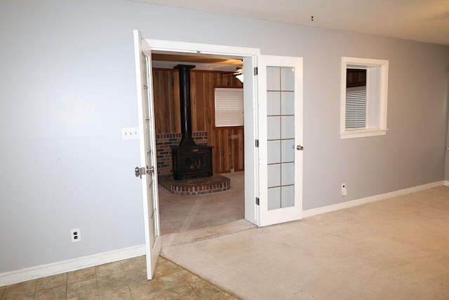 empty room featuring a wood stove, light carpet, and ceiling fan