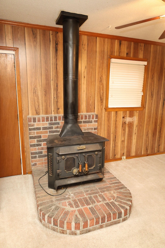 details with a wood stove, a textured ceiling, wooden walls, ornamental molding, and carpet