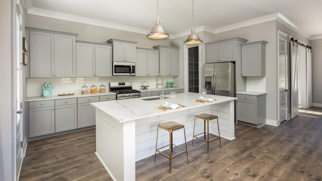 kitchen featuring gray cabinetry, sink, a barn door, appliances with stainless steel finishes, and dark hardwood / wood-style flooring