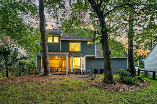 back house at dusk with central AC unit and a patio area