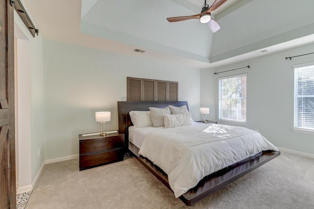 carpeted bedroom with ceiling fan, a barn door, vaulted ceiling, and multiple windows