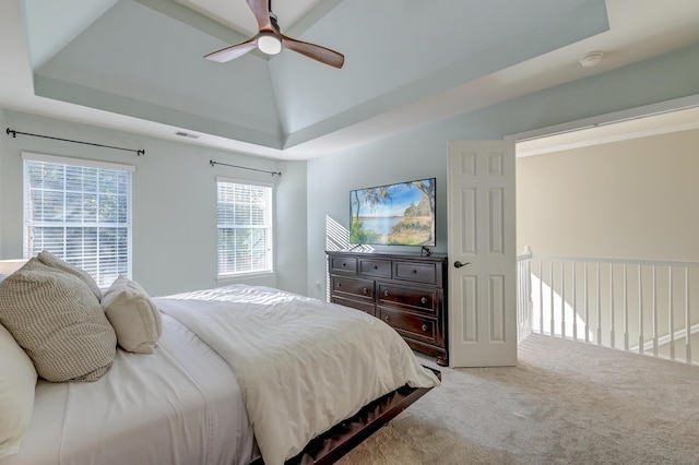 bedroom with light colored carpet, ceiling fan, and a tray ceiling