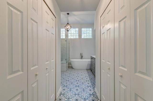 bathroom with tile patterned flooring, vanity, an inviting chandelier, and plus walk in shower