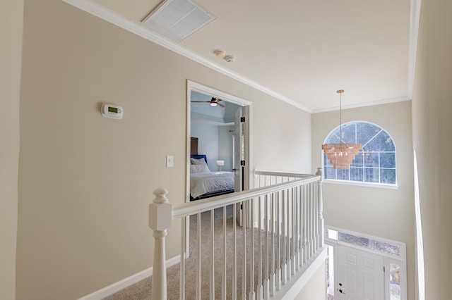 hall featuring carpet flooring, crown molding, and a chandelier