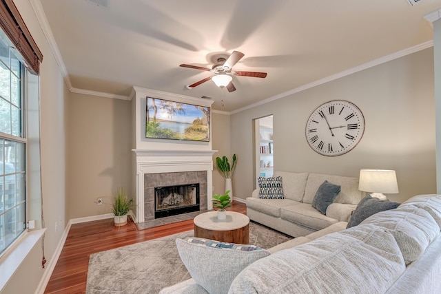 living room with hardwood / wood-style floors, ornamental molding, and a tiled fireplace