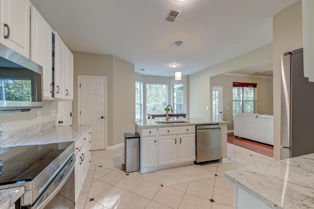 kitchen with light stone counters, stainless steel appliances, sink, pendant lighting, and white cabinets