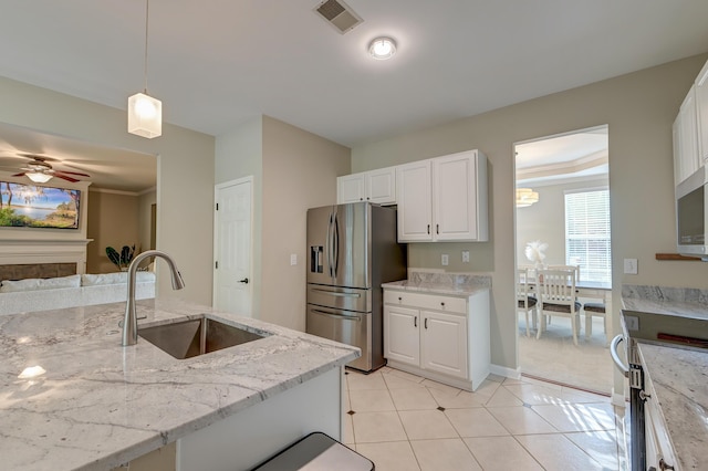 kitchen with stainless steel fridge, stove, white cabinetry, and sink